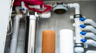 Old and new iron filter cartridges installed in a whole-home iron water filter system